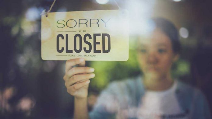 Hand hanging a closed sign on a shop door