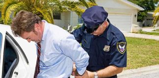 California Heir ARRESTED — But Something’s Off A police officer handcuffing a man in formal attire outside a police car