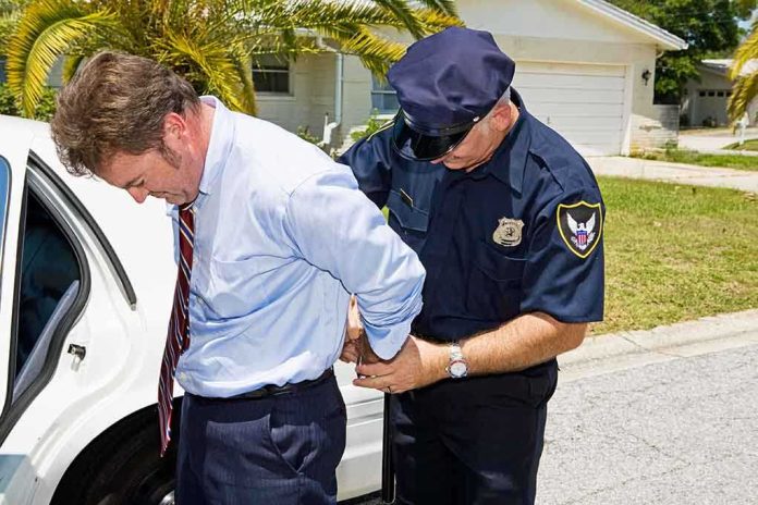 shutterstock_17843134 A police officer handcuffing a man in formal attire outside a police car