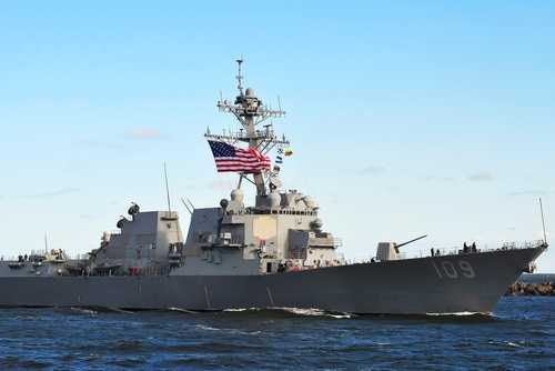 shutterstock_2259444639 naval destroyer with flags sailing on open water