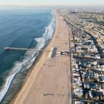 ANOTHER Unprovoked Shark Attack — What’s Going ON? Aerial view of a beach with a pier and urban area beside the ocean