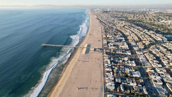 Aerial view of a beach with a pier and urban area beside the ocean