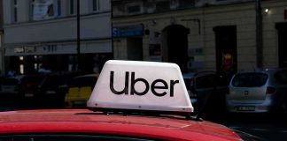 Uber SHOCK — State REWRITES the RULES Uber sign on top of a red car in an urban setting