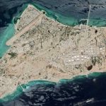 What Trump is EYEING NOW — When CONTROL is CRITICAL — JUST BUY IT! Aerial view of an industrial island with tanks, runway, and piers
