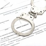 LATEST Chilling Trump Threat — VILE Online RANT Handcuffs on top of an arrest warrant document.