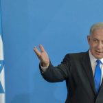 DANGEROUS Gamble — Israel Picks A PRINCE? Man in suit gestures beside Israeli flag.