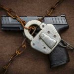 July 4TH GUN WAR Erupts Pistol locked with chains and a padlock.