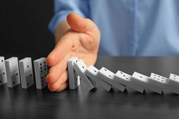 509251924 Hand stopping falling row of dominoes.