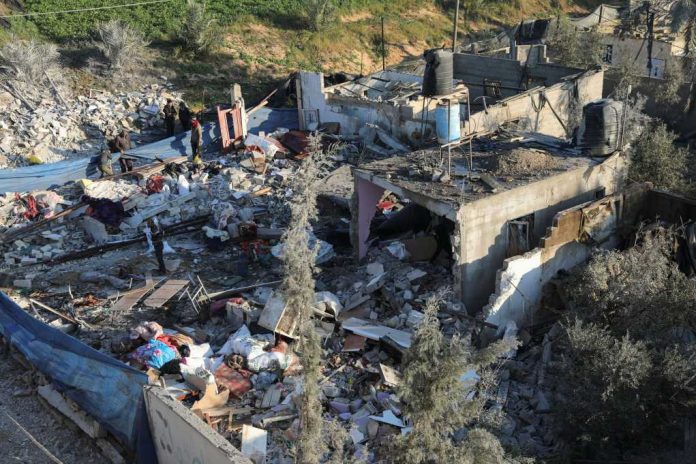 People inspecting rubble and debris of destroyed buildings.