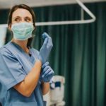 Prison Pedophile PROTECTED — Nurse GETS PUNISHED! Nurse wearing scrubs and mask putting on gloves.