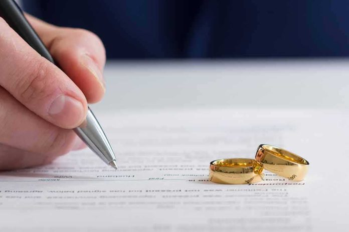 shutterstock_1043592691 Hand signing a document beside two gold wedding rings
