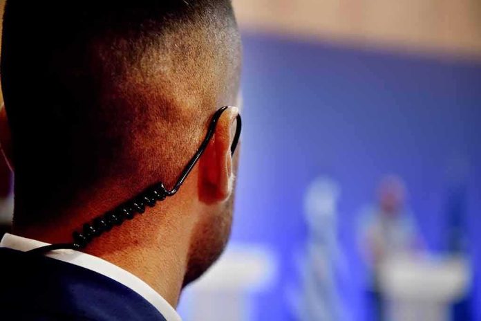 shutterstock_1127344769 Security guard with earpiece watching a blurred event stage