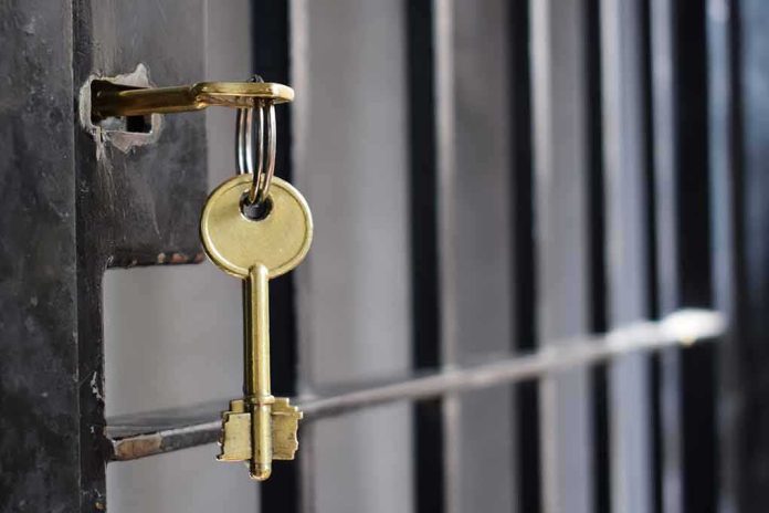 shutterstock_1134195950 Golden key hanging from a lock on a metal jail cell door