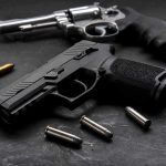 TRIPLE EXECUTION Over $65 DISPUTE! Handgun and revolver with scattered bullets on dark surface
