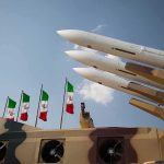 Iran Drops ‘FULL-SCALE WAR’ Bomb Missile launchers on a military vehicle with flags in the background