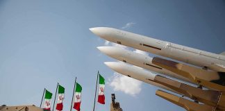 Iran Drops ‘FULL-SCALE WAR’ Bomb Missile launchers on a military vehicle with flags in the background