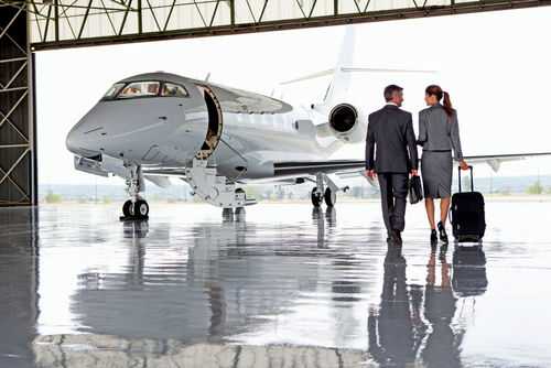 shutterstock_1862081296 Two businesspeople walking towards a private jet in hangar.