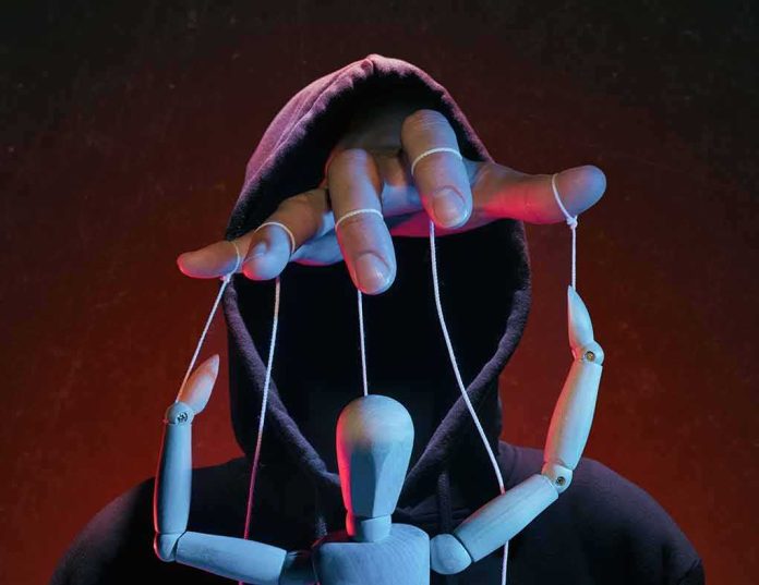 Hooded figure controlling a wooden puppet with strings