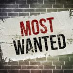 Ringleader Nailed — MOST WANTED Finally CAUGHT! A weathered poster displaying the words MOST WANTED on a brick wall
