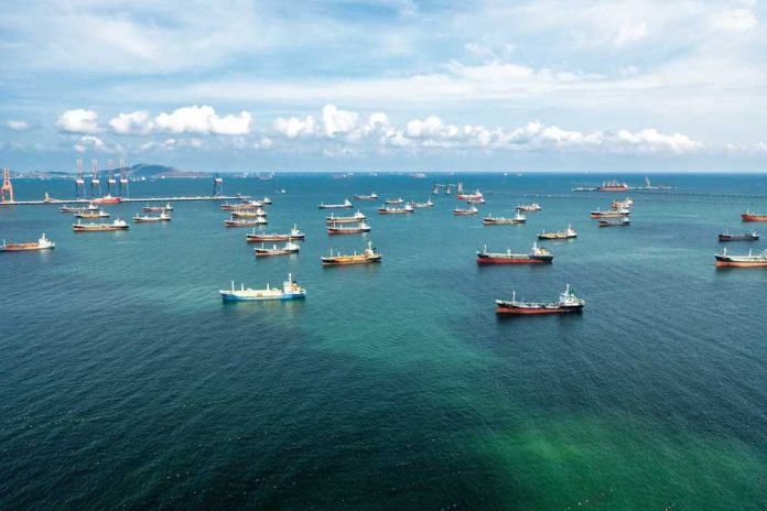 shutterstock_2627757273 Aerial view of numerous cargo ships anchored in a blue ocean