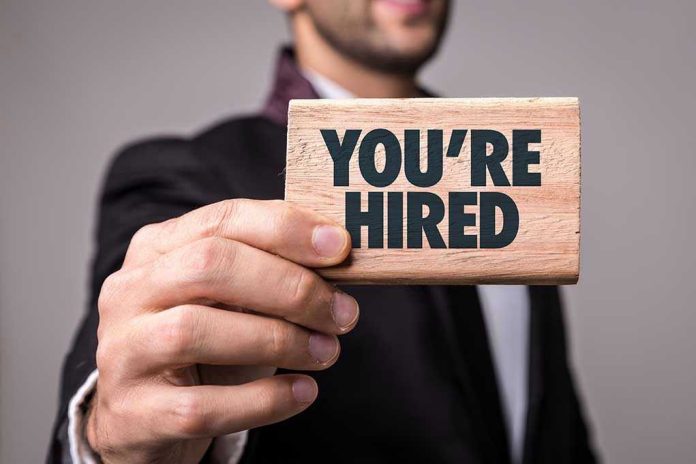 623590175-1 Person holding a Youre Hired sign.
