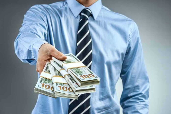 shutterstock_1008204853 Person in business attire offering bundles of US dollar bills