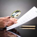SCANDAL — Judges’ Opinions FLAGGED as AI-Written Hands holding magnifying glass over contract document
