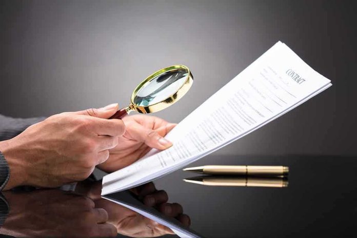 shutterstock_1016367745 Hands holding magnifying glass over contract document