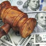 $410K Payout After PRONOUN Standoff Wooden judge's gavel on scattered US dollar bills