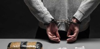 ISIS Pledge — NEW BOMB Plot Exposed person in handcuffs behind back over table with seized packages