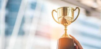 Award Winner Tied to TRAFFICKING RING! Hands holding a golden trophy cup