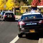 SHOCKING Classroom Massacre — HEARTBREAK Police cars with flashing lights near school buses on a city street