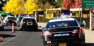 SHOCKING Classroom Massacre — HEARTBREAK Police cars with flashing lights near school buses on a city street