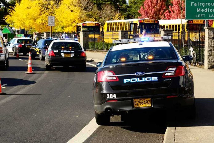 shutterstock_117302929-1 Police cars with flashing lights near school buses on a city street