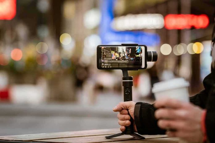 shutterstock_1682035603 Smartphone on a handheld gimbal filming a city street at night