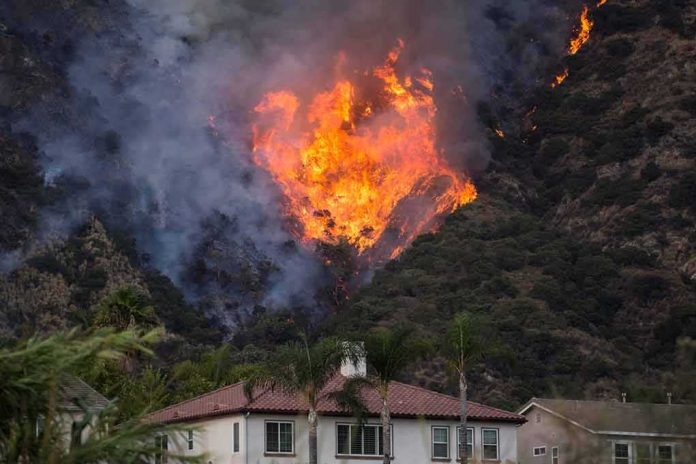 shutterstock_1795511017 Wildfire burning on a hillside near homes
