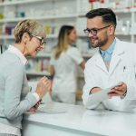Drug Prices PLUNGE — What’s Behind It? Pharmacist assists customer at pharmacy counter