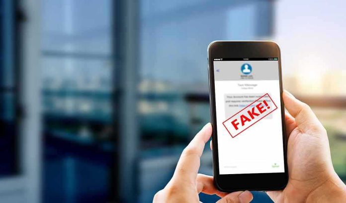 Hands holding smartphone showing scam text marked fake
