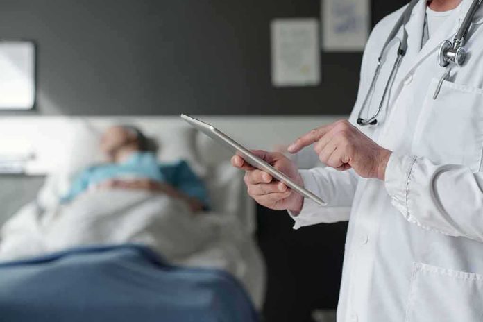 shutterstock_2316812635-2 Doctor using tablet beside hospital patient