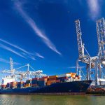 Missiles Near Dubai — Trade Slams SHUT Container ship docked at port with cranes loading cargo