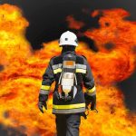MASSIVE Blast Rocks Ammo Plant Firefighter in protective gear facing large flames