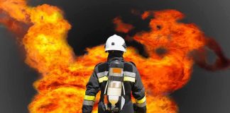 MASSIVE Blast Rocks Ammo Plant Firefighter in protective gear facing large flames