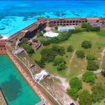 STUNNING NEWS — East Coast GOLDEN DOME Shield Debuts Aerial view of a coastal brick fort with moat and turquoise sea