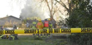 Wildfire Whodunit — BIZARRE Arrest DETAILS REVEALED Yellow police tape marking a restricted area at a fire scene with firefighters in the background