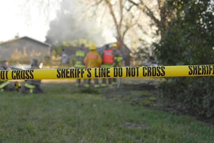 shutterstock_5838397 Yellow police tape marking a restricted area at a fire scene with firefighters in the background