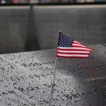 Chilling Warning From Bush American flag on a rainy memorial nameplate.