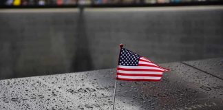 Chilling Warning From Bush American flag on a rainy memorial nameplate.