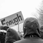 The UK Just Got A Breakup Letter — Signed Three Times crowd in winter coats at a protest holding a sign