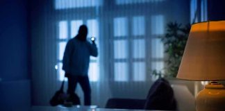 Doctor Woke To A Knife Attack — Look What The Intruder WORE Silhouetted intruder in a dim living room at night