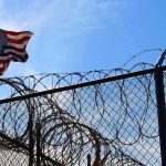Intruder Hit The Base That Runs Our Iran War — They Won’t Say WHO American flag near barbed wire fence against blue sky